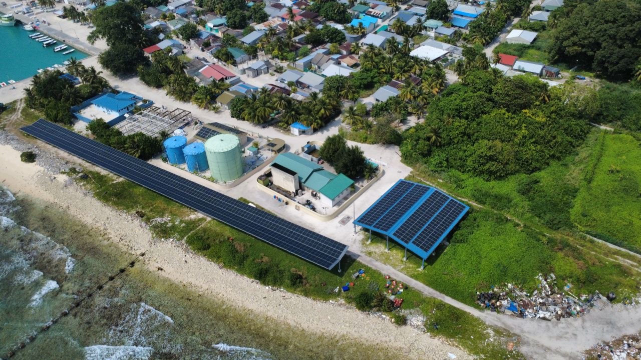 Coastal solar plant and village rooftops beside the shoreline