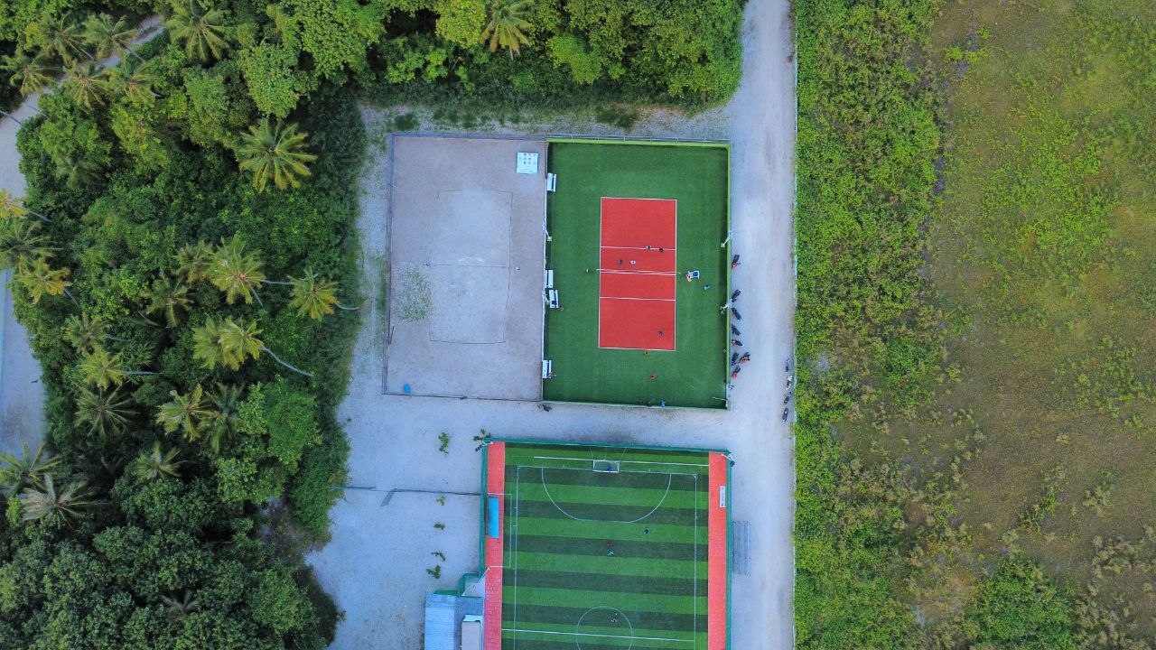 Futsal pitch and sports courts surrounded by palm trees